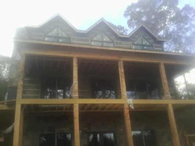 Dormers and porch framing on a large log home under construction — Roof Coating work by our crew in Franklin Square