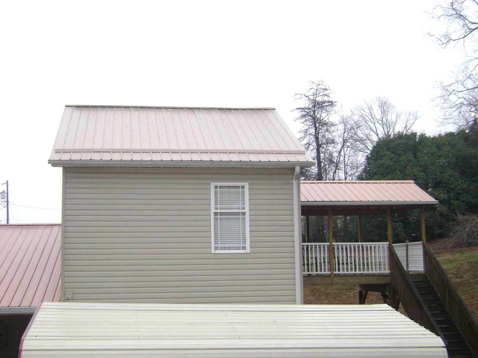 Tan metal roofs on a two story addition and attached porch, from a Roof Replacement job in Franklin Square
