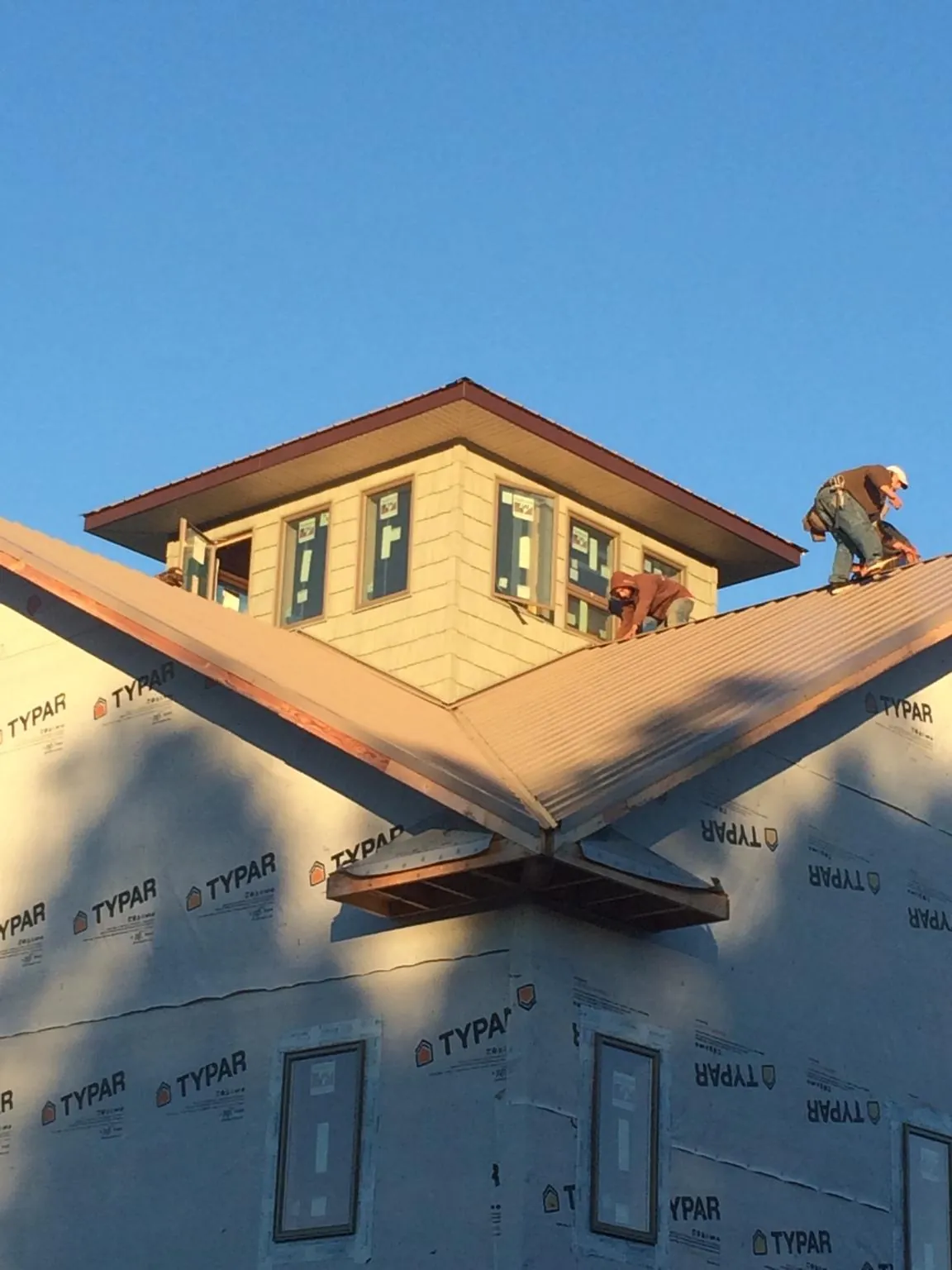 Roofers working around a rooftop cupola on a new metal roof at sunset — Roof Waterproofing in Franklin Square by Roofing Brothers